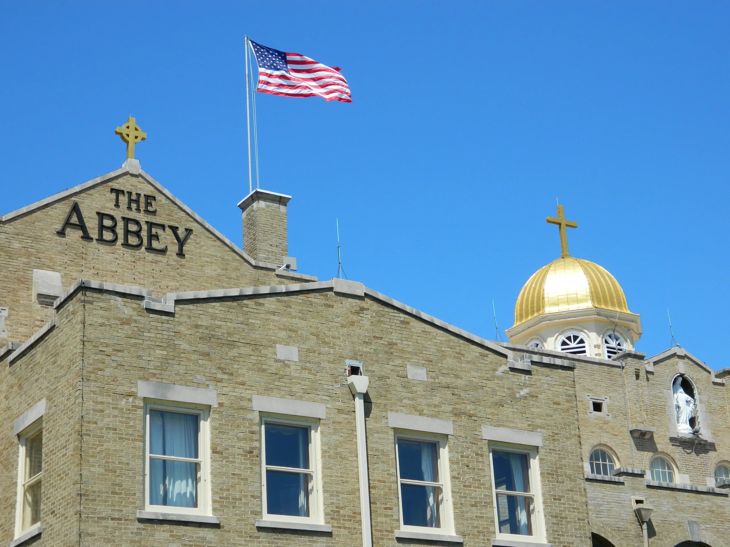 Brick building with a gold dome and 'THE ABBEY' sign on the facade under an American flag