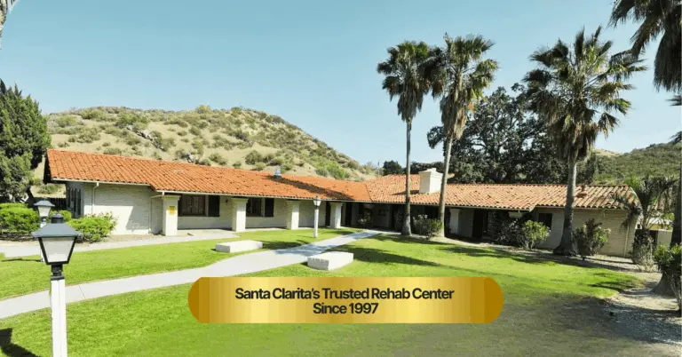 Single-story Spanish-style building with a red tile roof, palm trees and a green lawn
