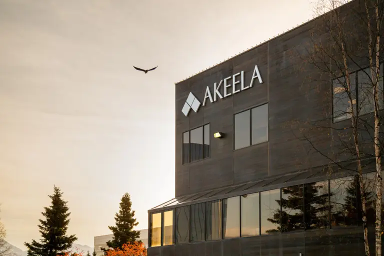 Dark multi-story building with AKEELA sign on its facade under a warm evening sky