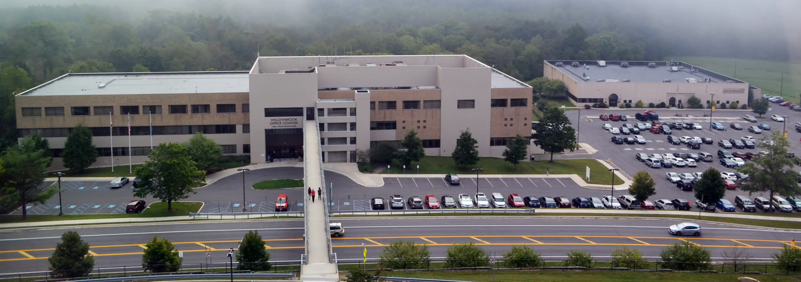 Aerial view of the Willowbrook Office Complex, a multi-story building with a large parking lot and trees