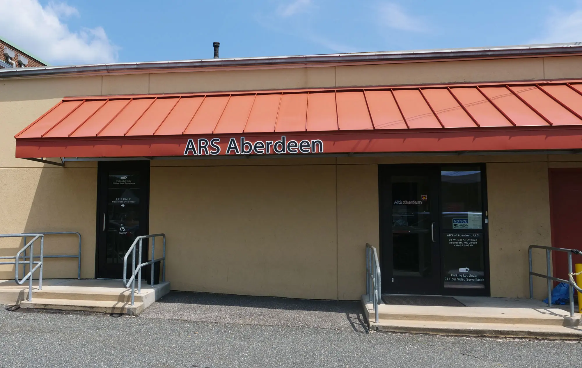 Tan storefront with orange awning and ARS Aberdeen sign over glass entrance doors