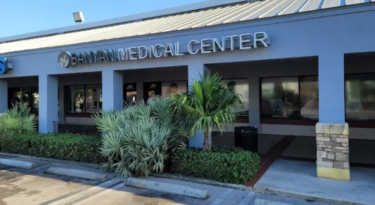 Two-story building with a Banyan Medical Center sign and logo above the entrance and a palm tree in front