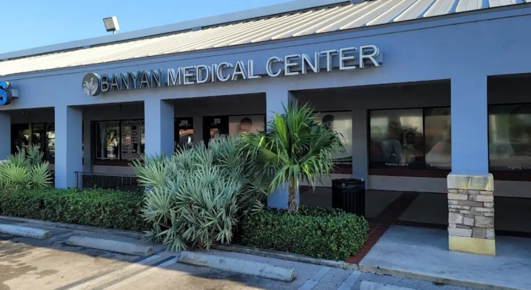 Two-story building with a Banyan Medical Center sign and logo above the entrance and a palm tree in front