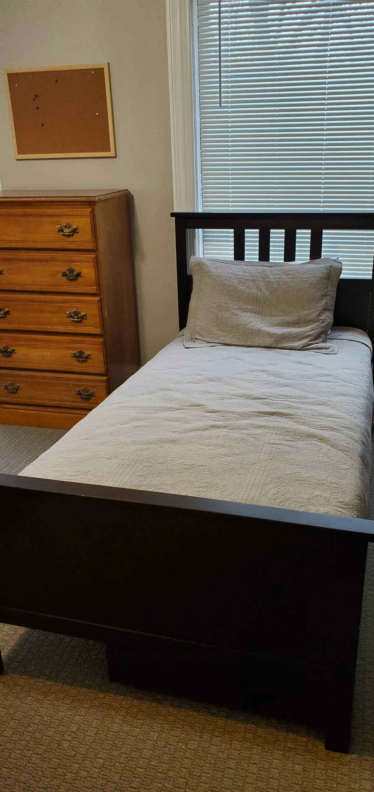 Single bedroom with a dark wood twin bed, a wooden dresser, and window blinds