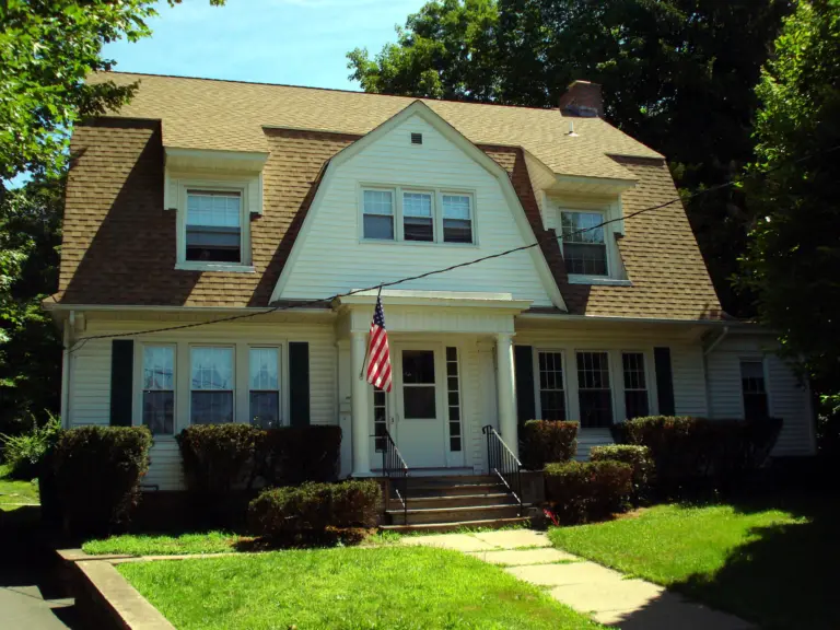 White two-story house with a flag and columned front porch