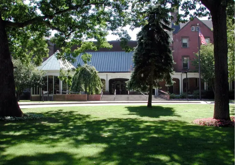 Butler Hospital entrance with a covered portico, brick building, lawn and mature trees