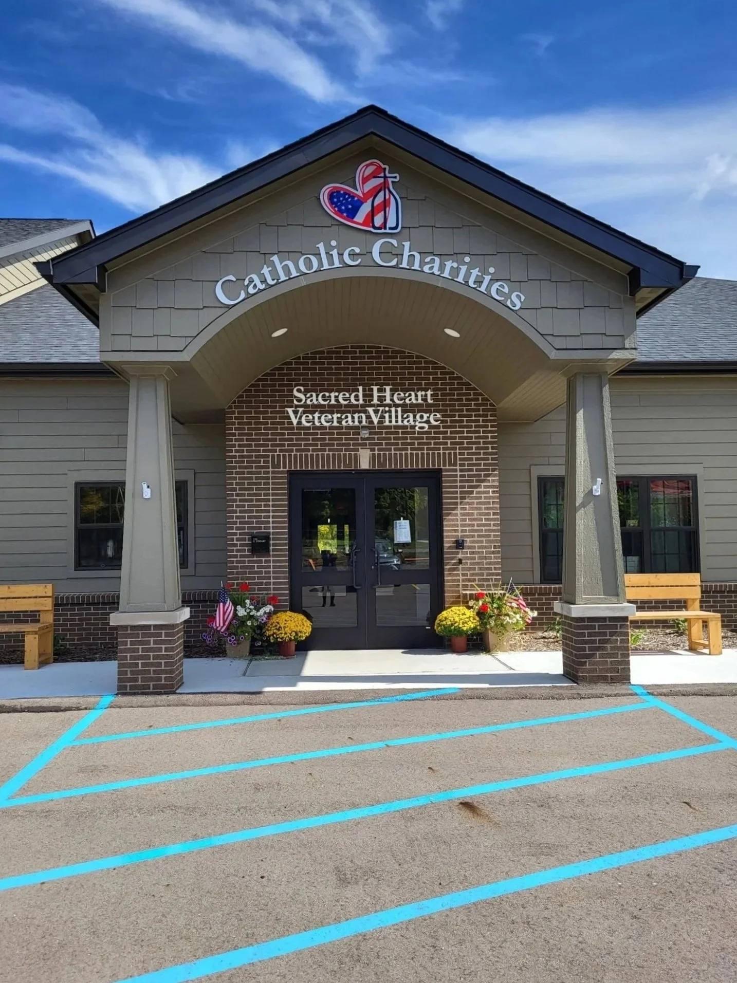 Brick and siding entrance of Sacred Heart Veteran Village with a Catholic Charities sign above the door