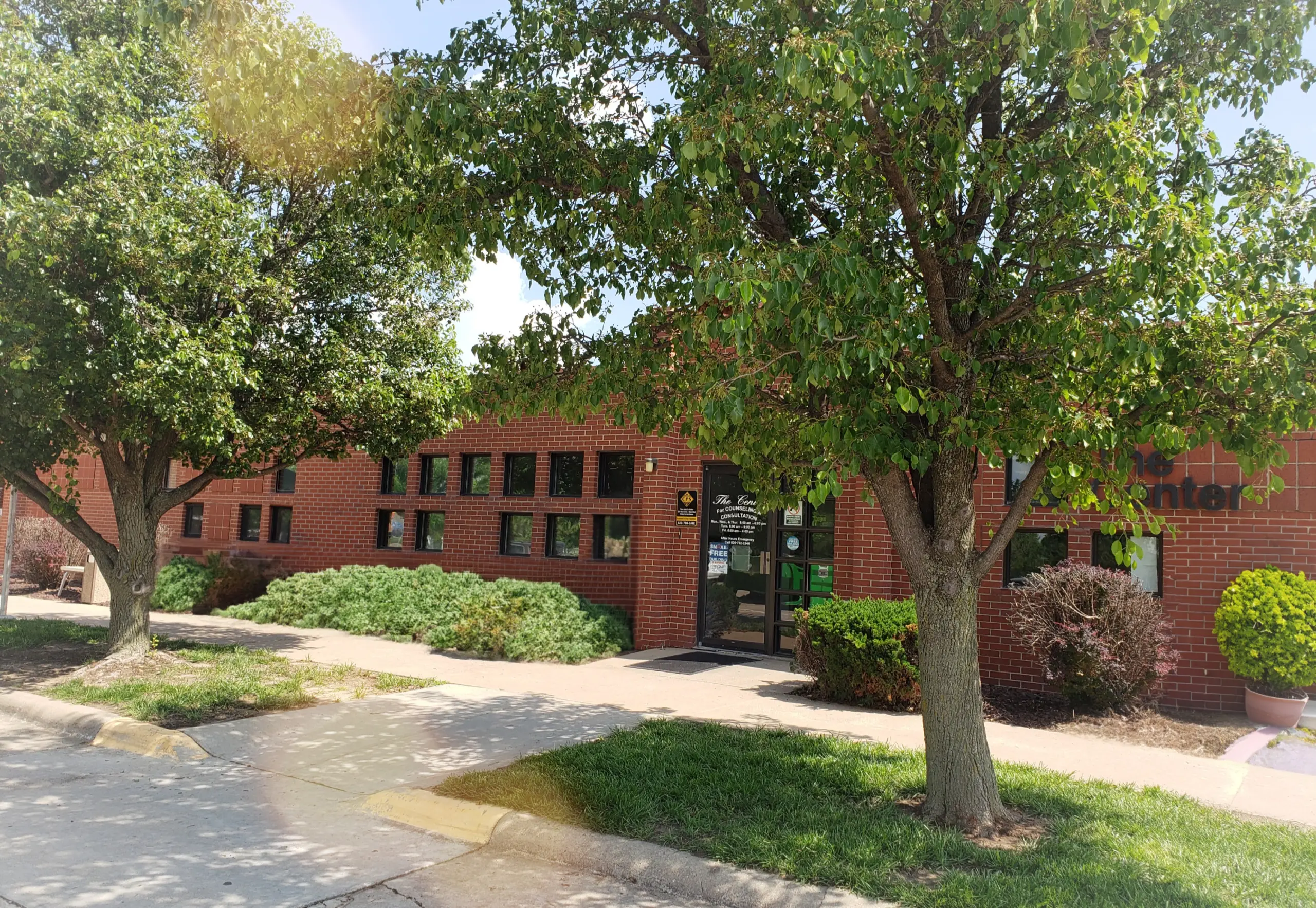 Brick building exterior with The Center for Counseling & Consultation sign and entrance, shaded by trees