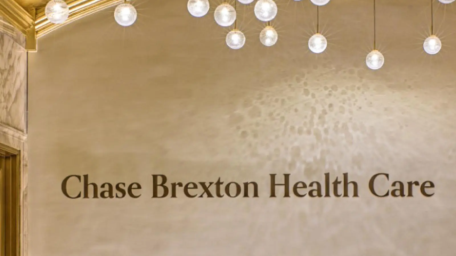 Lobby wall with Chase Brexton Health Care lettering under a row of warm pendant lights