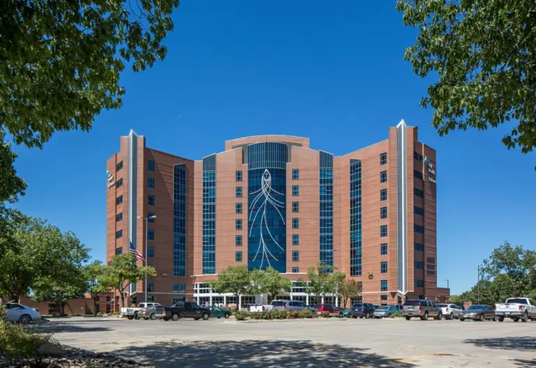 Multi-story brick hospital building with a CHI Health sign under a blue sky