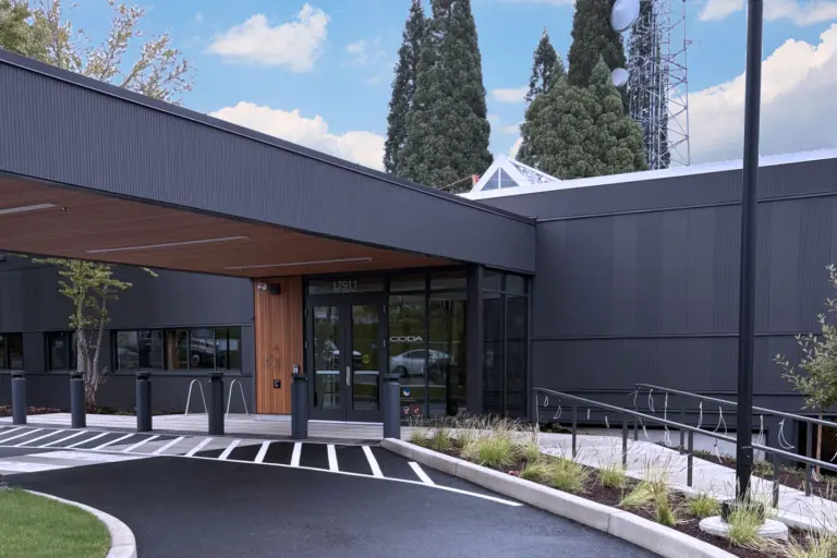 Modern dark-gray CODA building entrance with covered walkway and address 17911 above the doors