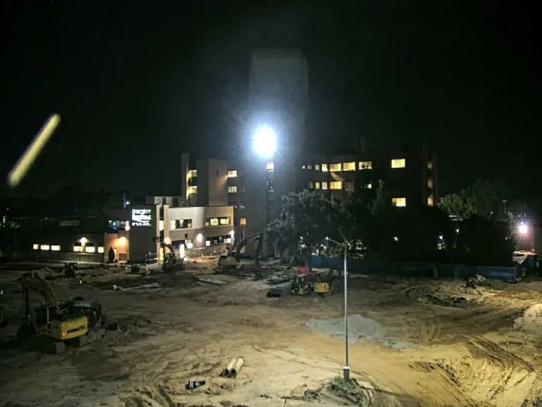 Nighttime view of hospital campus buildings with a construction site in the foreground