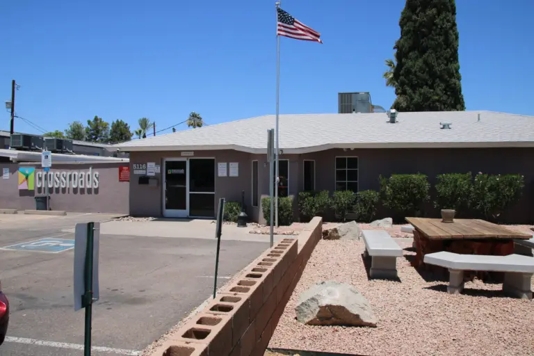 Single-story building with a Crossroads sign, flagpole, and outdoor picnic area
