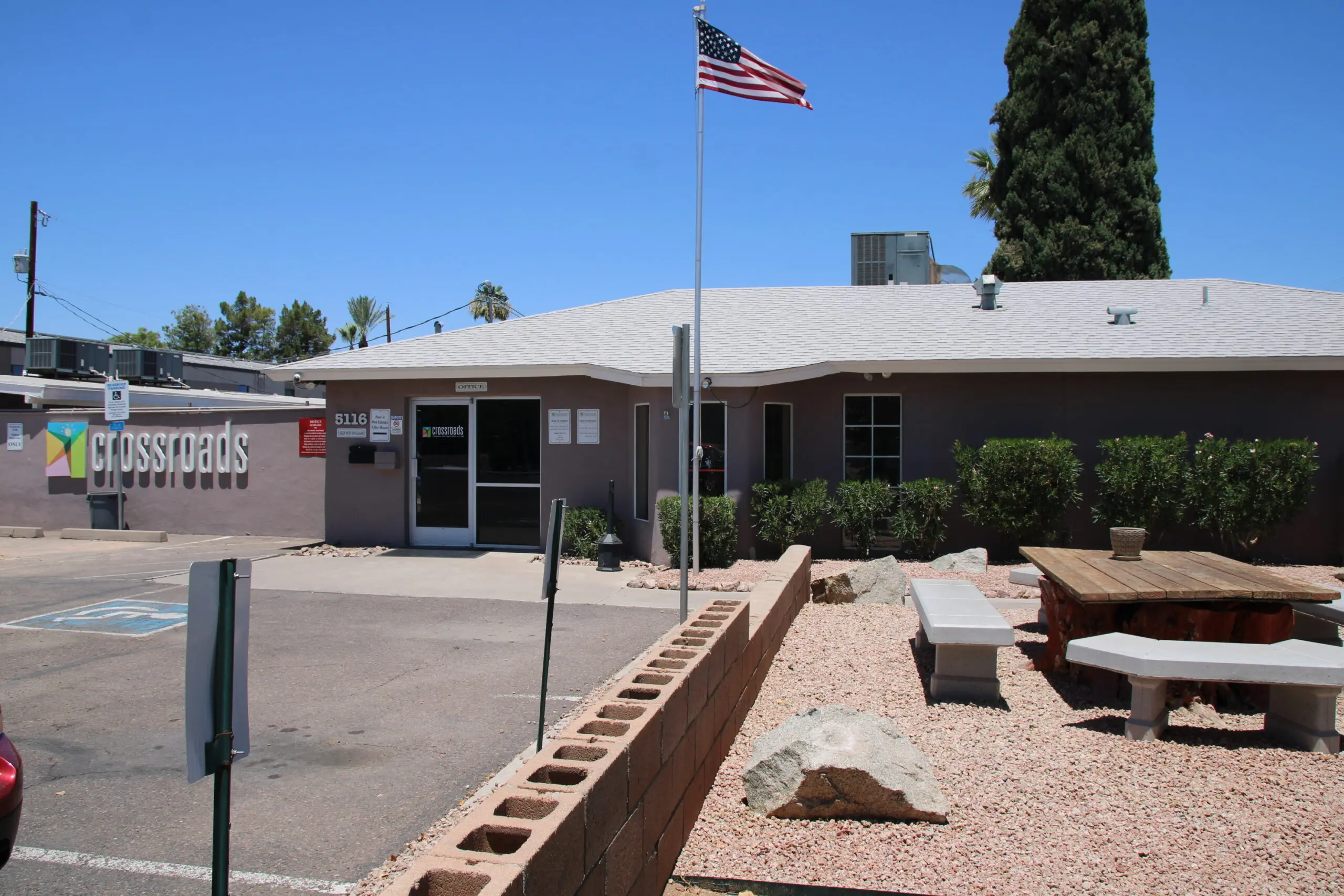 Single-story building with a Crossroads sign, flagpole, and outdoor picnic area