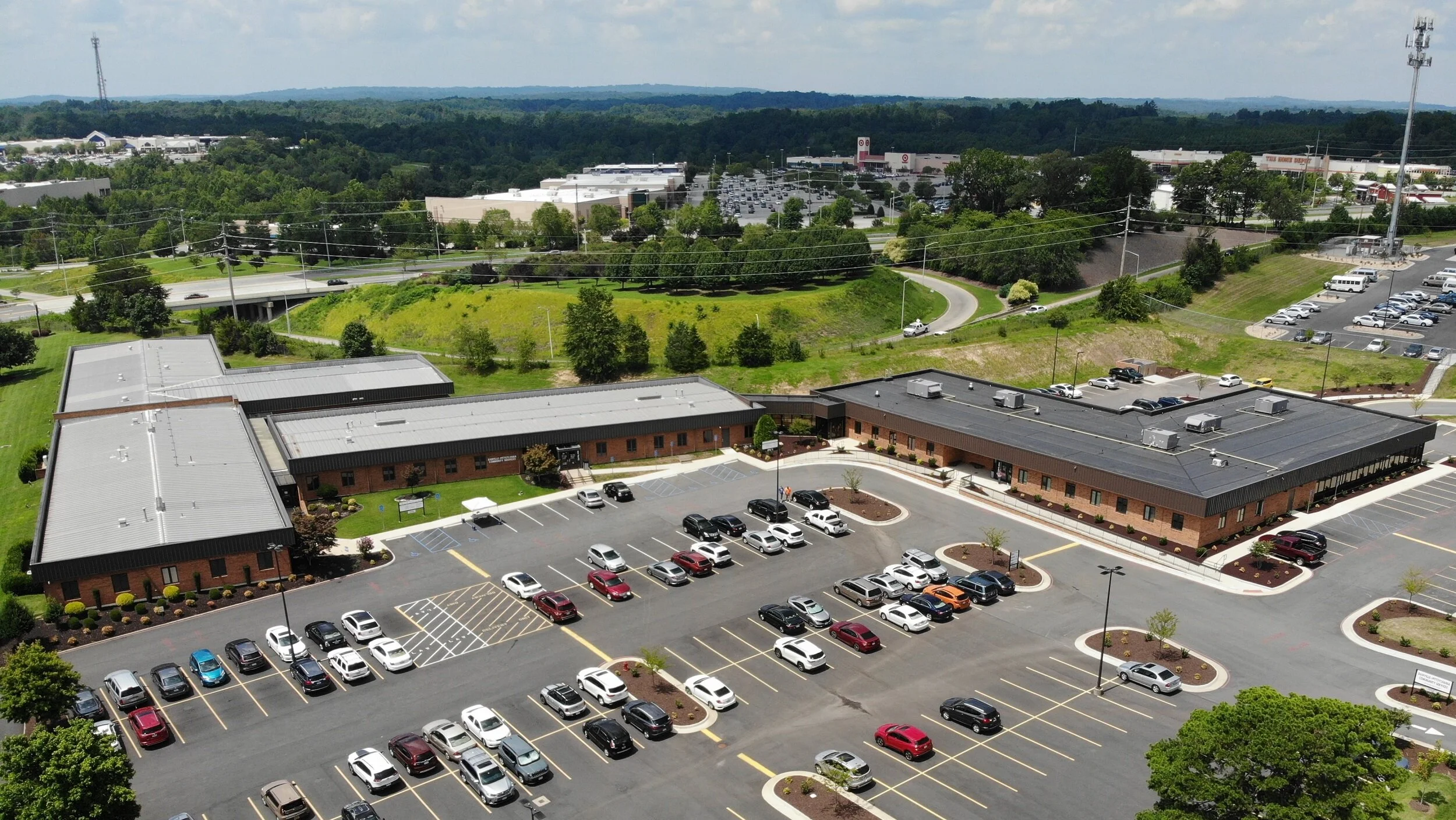 Aerial view of a brick campus with several low buildings, surrounding parking lots, and trees