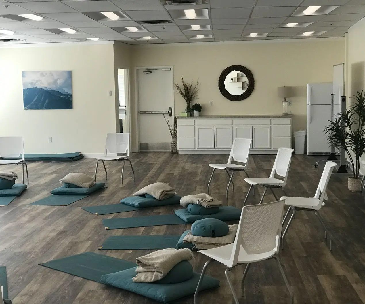 Mindfulness room with meditation cushions, floor mats, and white chairs along a wall