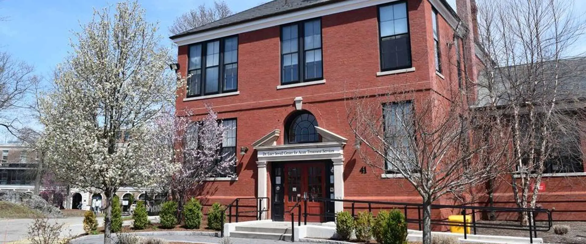 Red brick building with Dr. Lois Sewall Center for Acute Treatment Services sign over the entrance