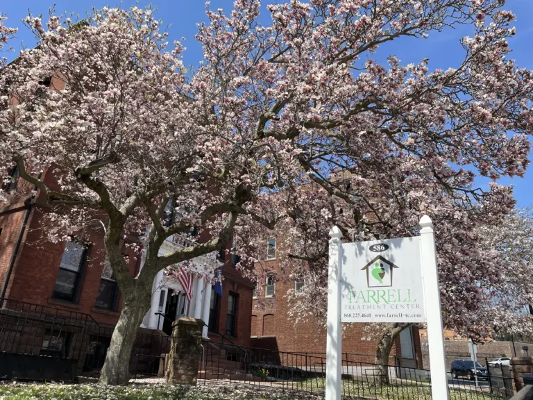 Brick building with a magnolia tree in bloom and a Farrell Treatment Center sign