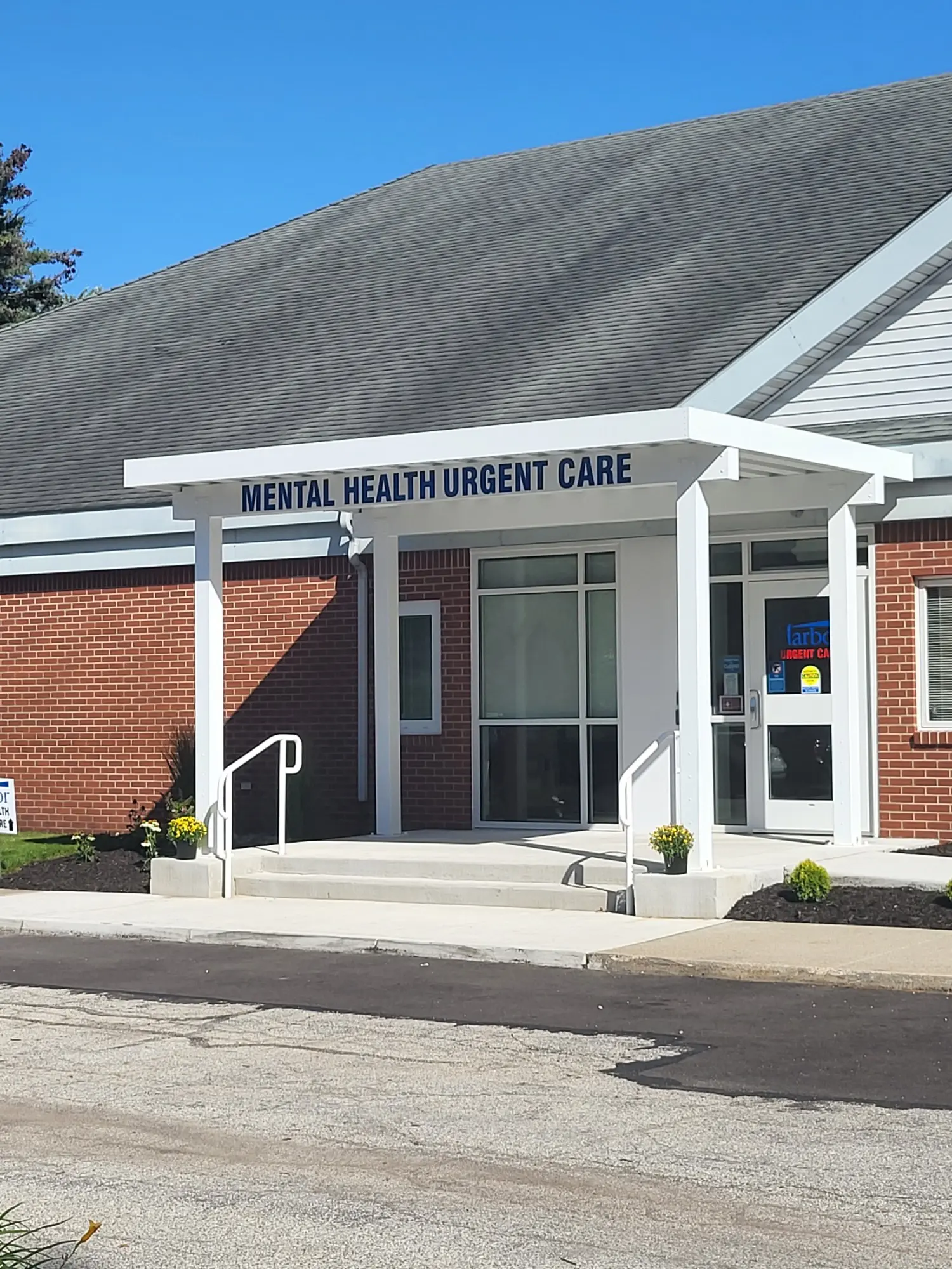 Brick building entrance with a Mental Health Urgent Care sign and white canopy