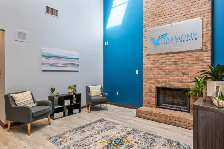 Lobby sitting area with two armchairs and a brick fireplace under a Harmony Healing Center sign