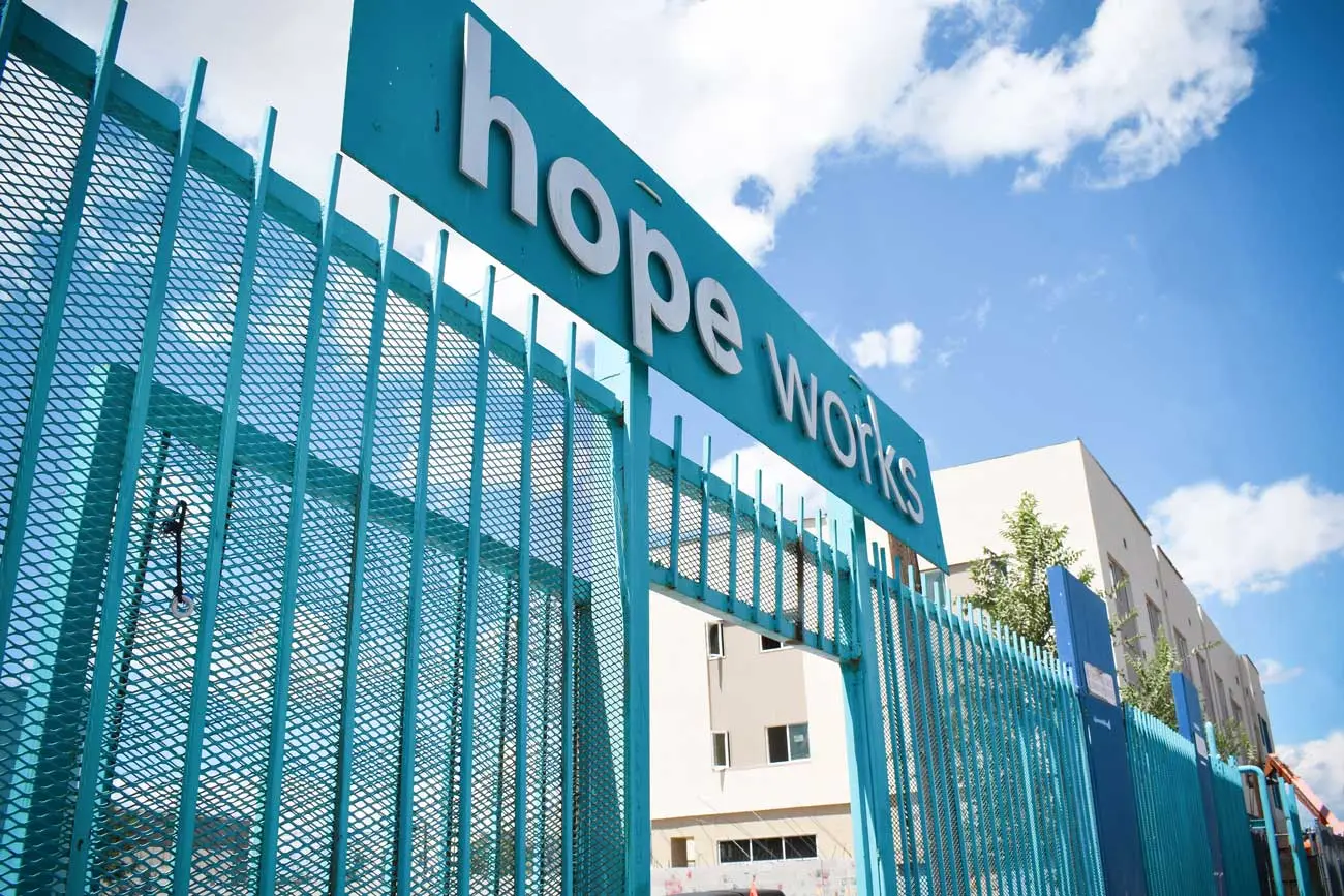 Teal entry gate with a hope works sign in front of a building