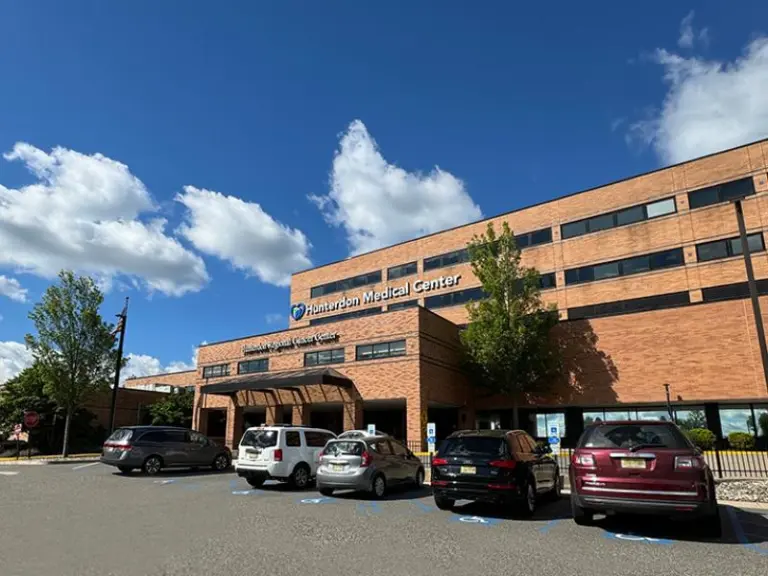 Brick Hunterdon Medical Center building with a covered entrance and parking lot under a blue sky