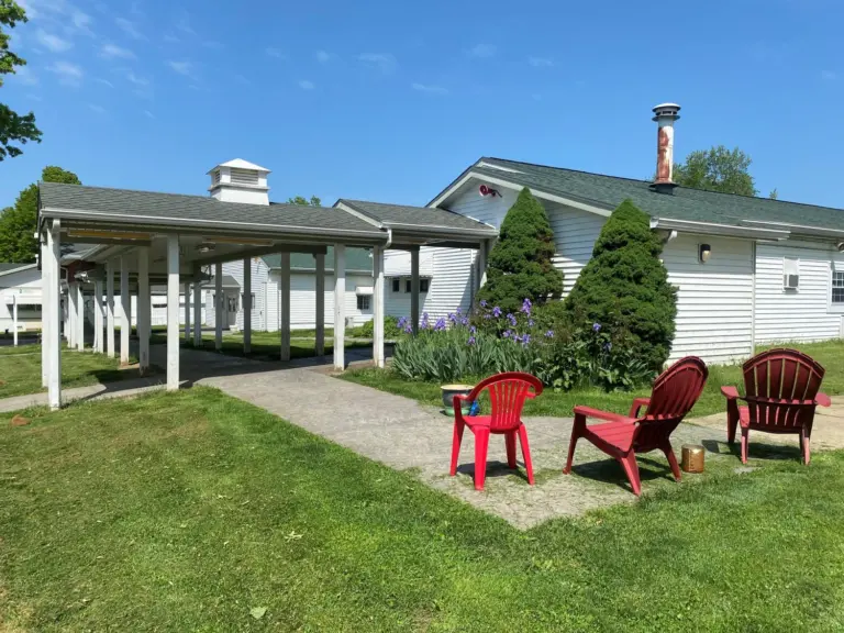White recovery house building with red chairs and flowering plants on a sunny lawn