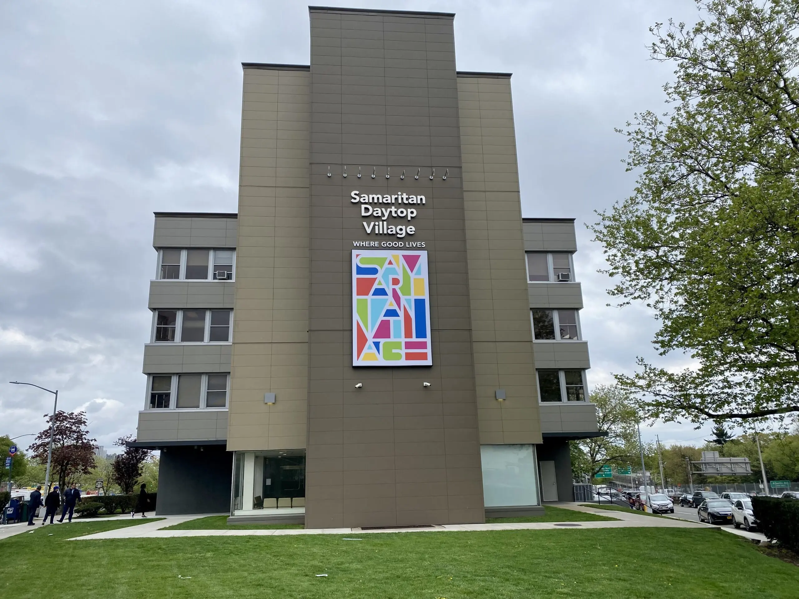 Four-story tan building with a Samaritan Daytop Village sign and a colorful Samaritan logo banner