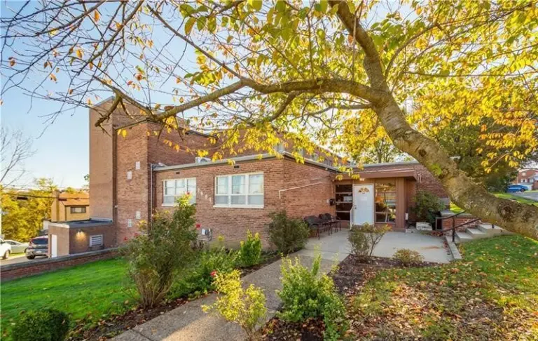 Two-story brick building with a tree and a walkway leading to the entrance