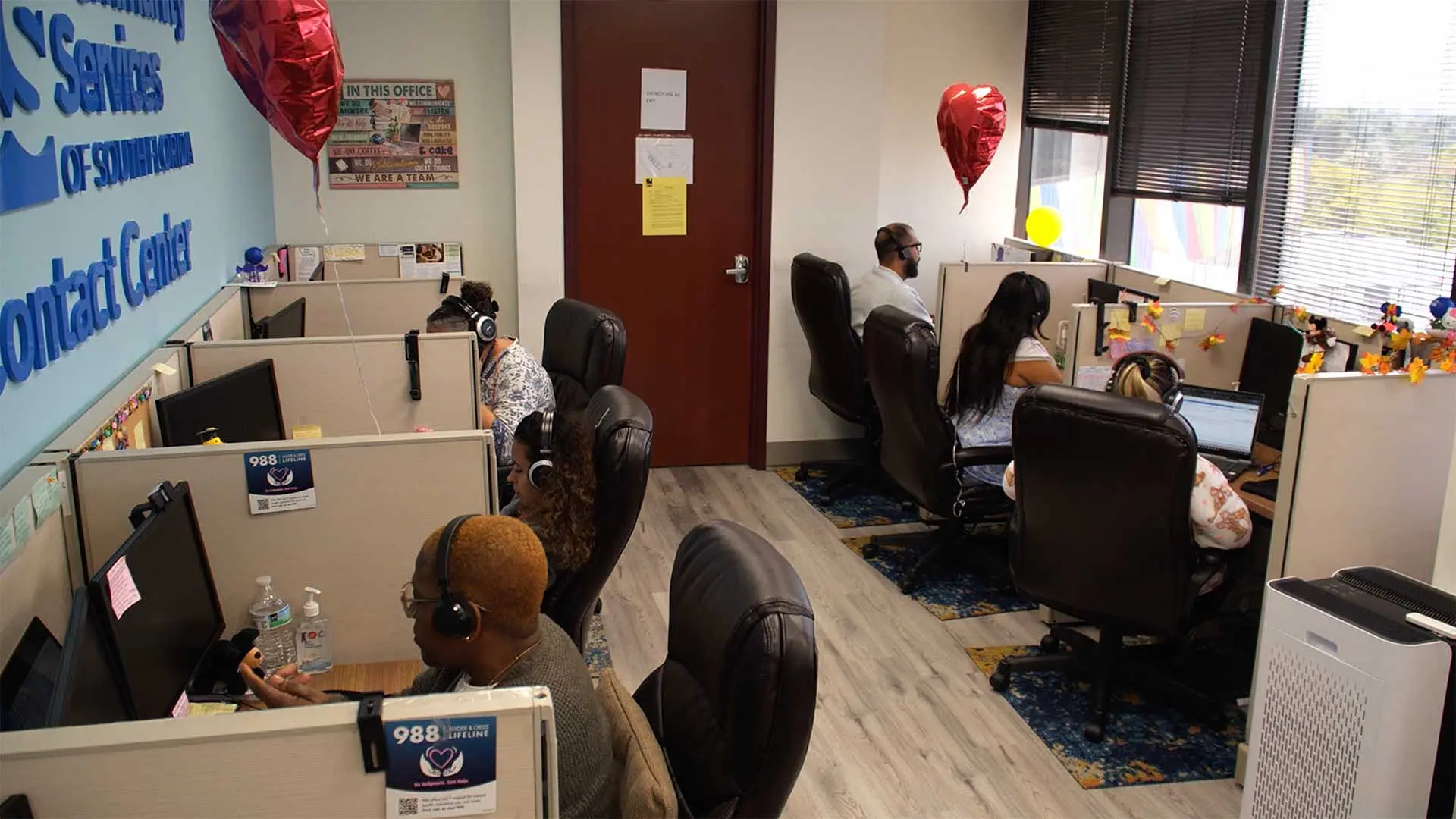Contact center office with rows of workstations beneath a Jewish Community Services of Southern Florida sign