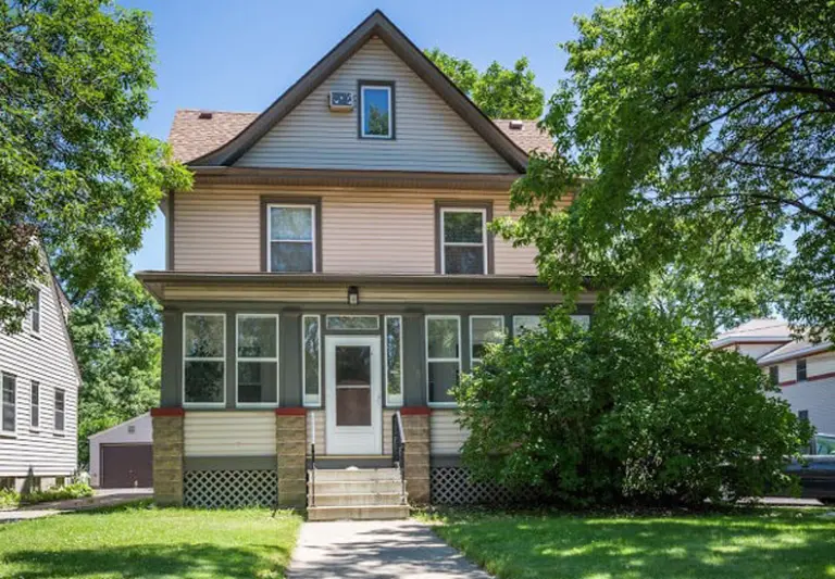 Two-story house with a covered front porch and a walkway through a lawn