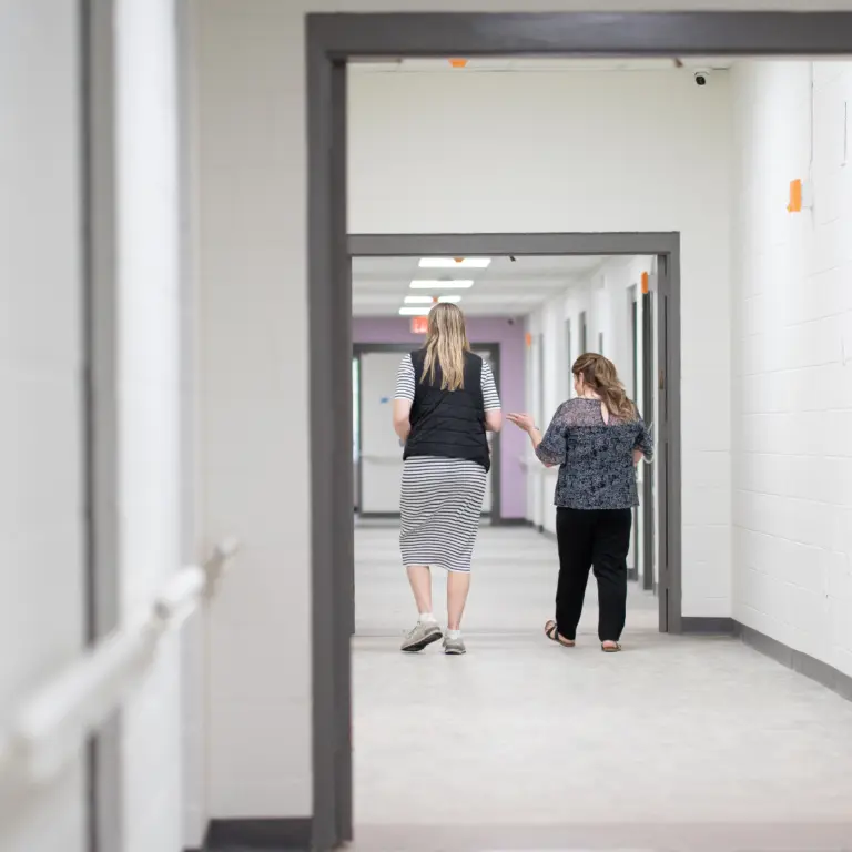 Long hallway with white block walls, gray door frames, and a purple accent wall at the far end