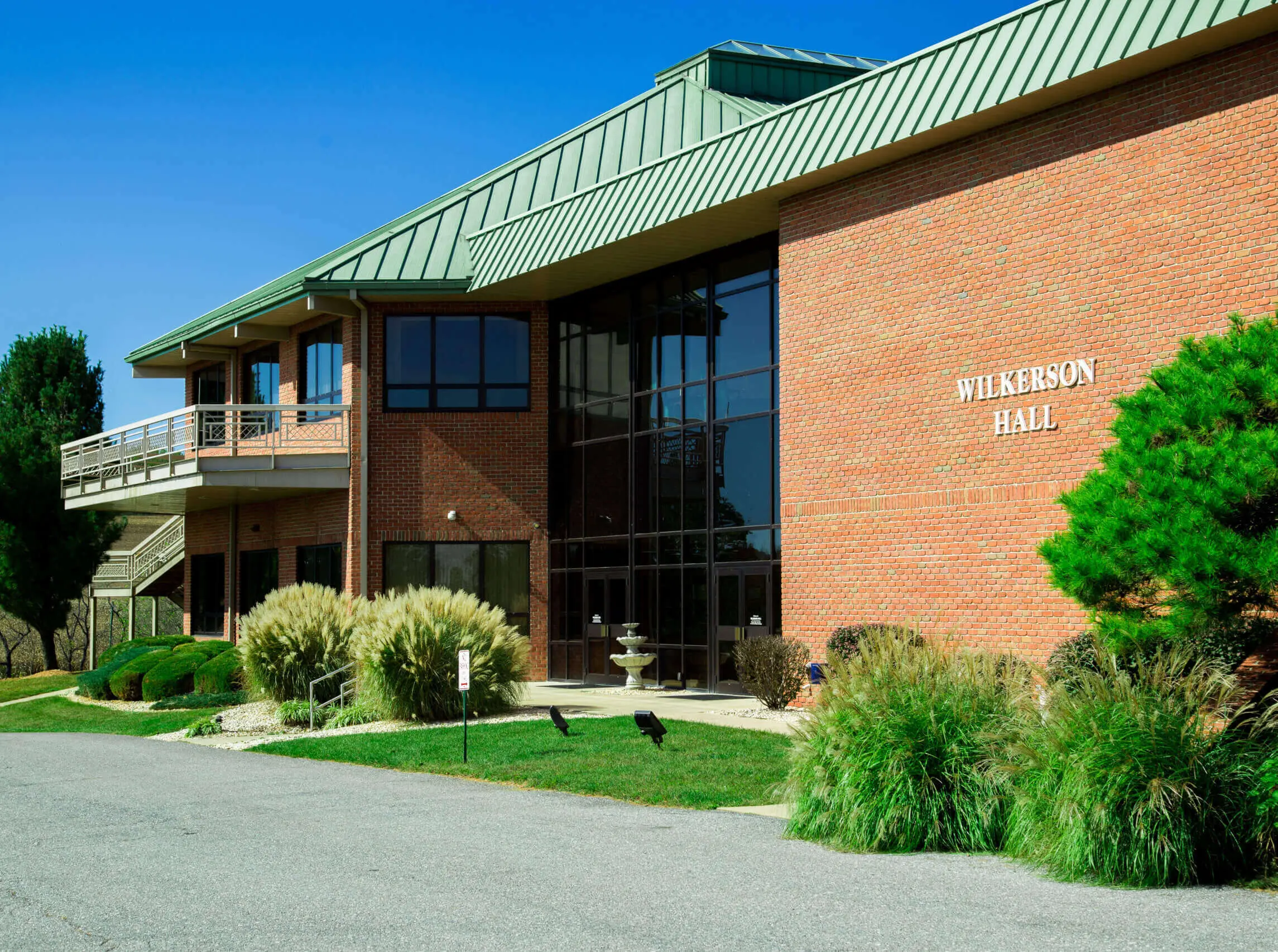 Two-story brick building with a green metal roof and a sign reading Wilkerson Hall
