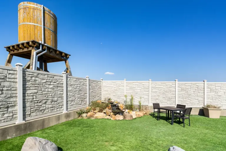 Backyard garden with a rock waterfall, artificial turf lawn, and a patio table set
