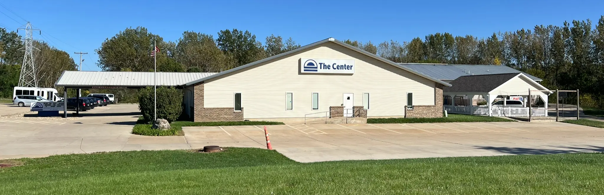 Single-story tan building with a brick base and a The Center sign, with a parking lot in front