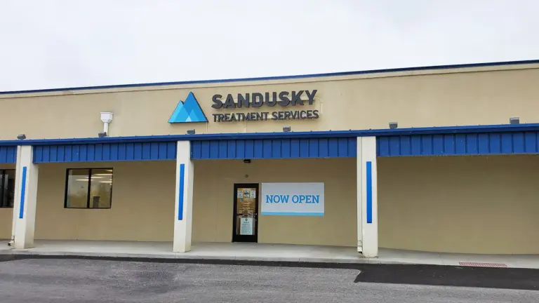 Single-story tan building with a Sandusky Treatment Services sign and a Now Open banner