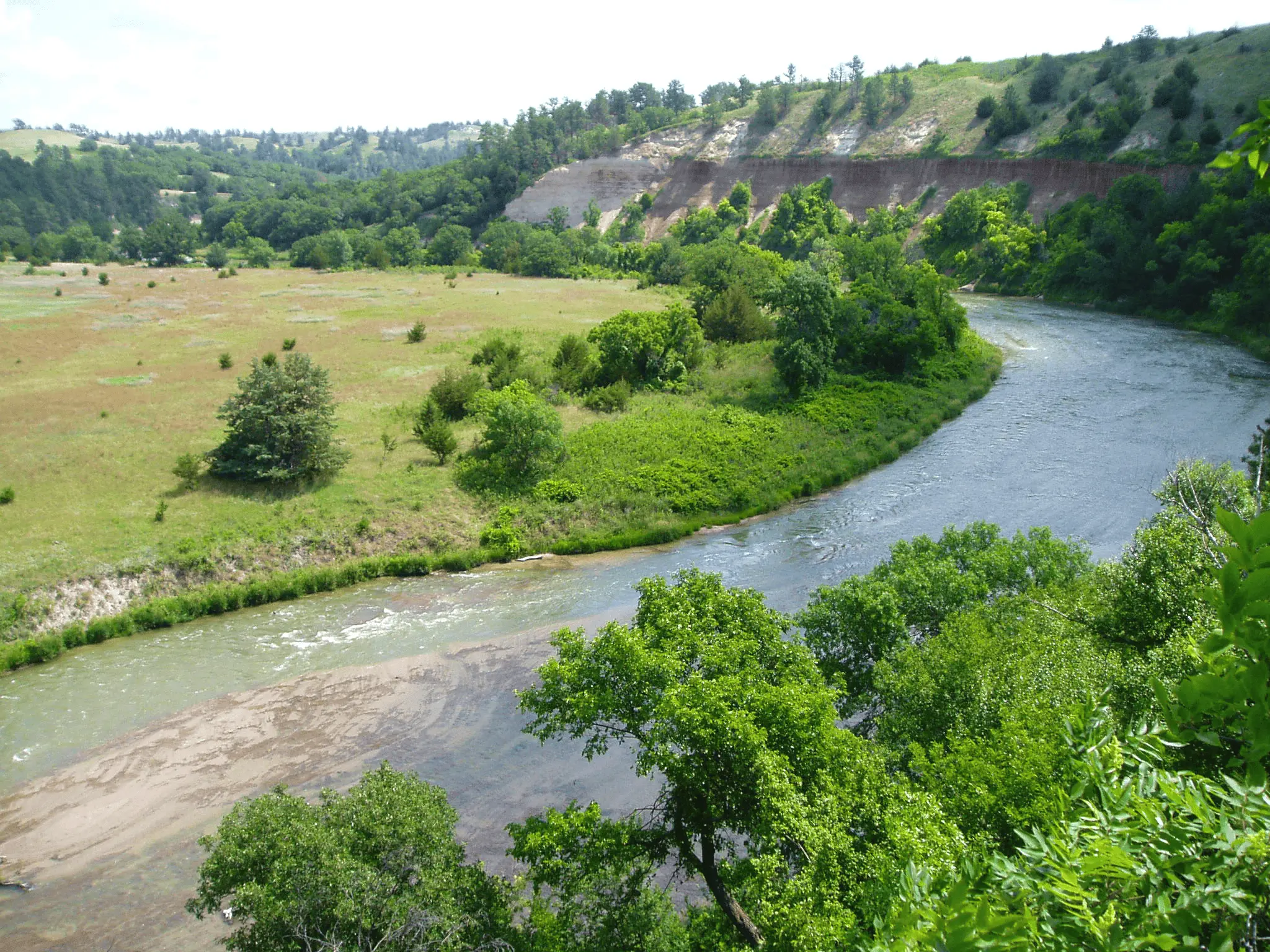 Niobrara River winding through a green valley with grassland and wooded bluffs