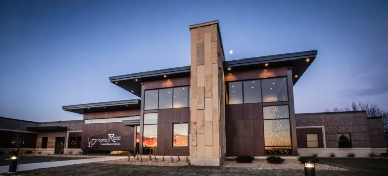 Modern two-story building with a stone tower and Prairie Ridge Integrated Behavioral Healthcare sign at dusk