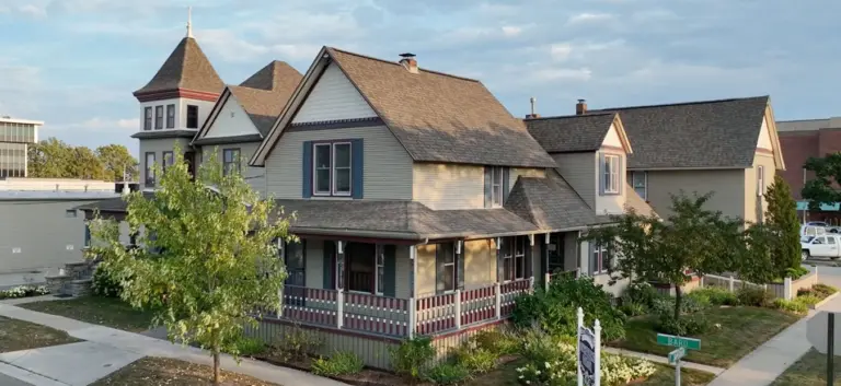 Victorian-style house with a wraparound porch and green street sign
