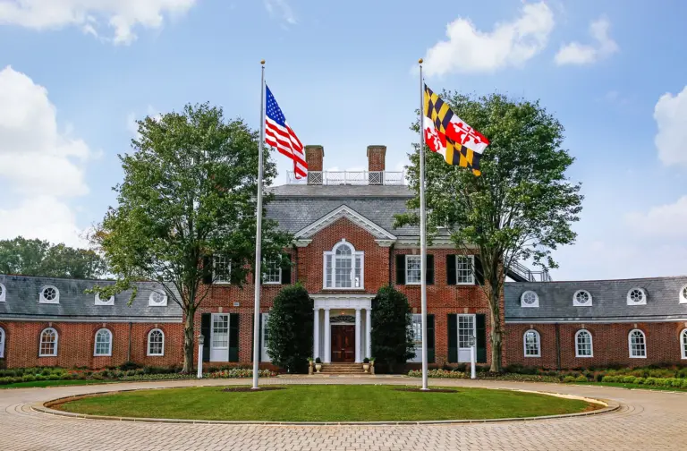 Brick colonial-style building with American and Maryland flags and a circular brick driveway
