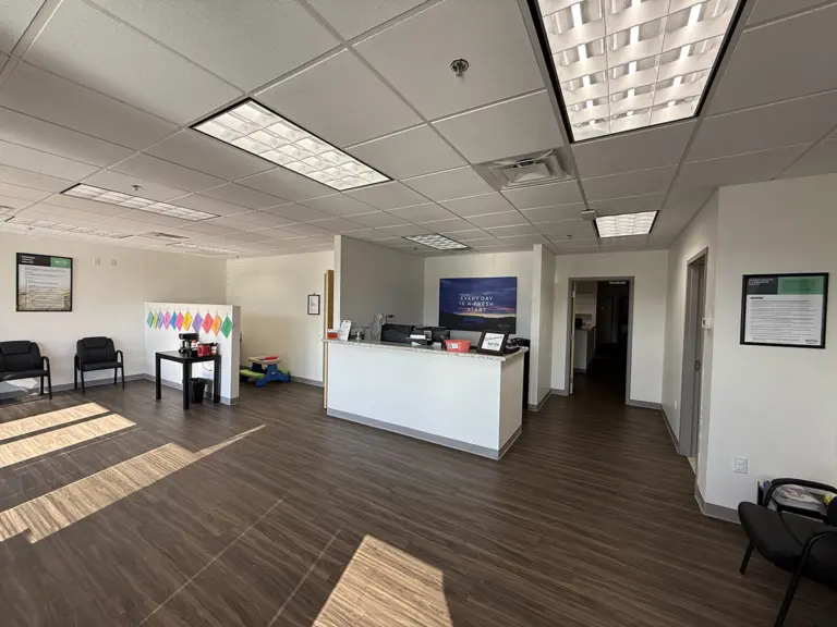 Reception lobby with granite front desk, waiting chairs, and a ReVida 'Every day is a fresh start' banner