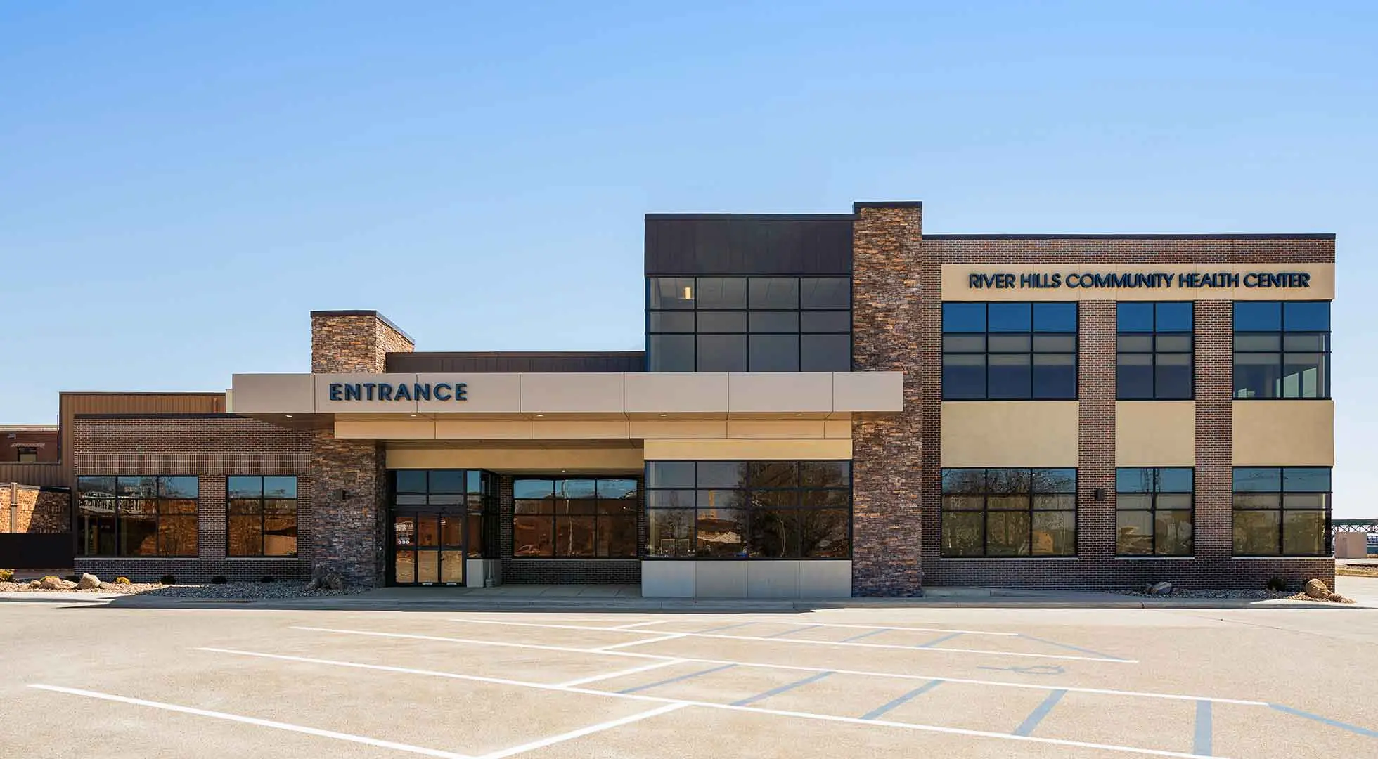 Brick and stone two-story building with a River Hills Community Health Center sign and entrance canopy
