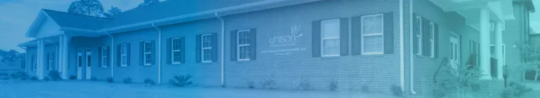 Single-story brick building with a Unison sign and a blue-tinted overlay, with columns at the entrance
