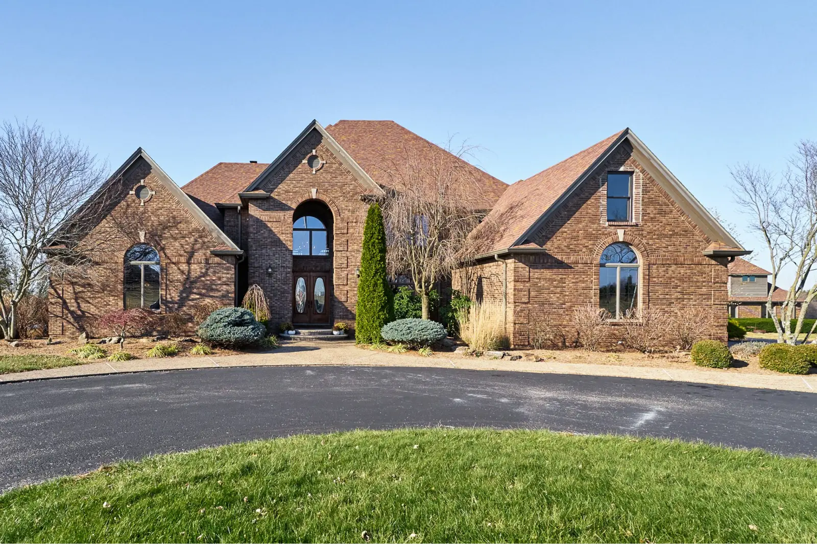 Two-story brick house with arched windows and a circular driveway