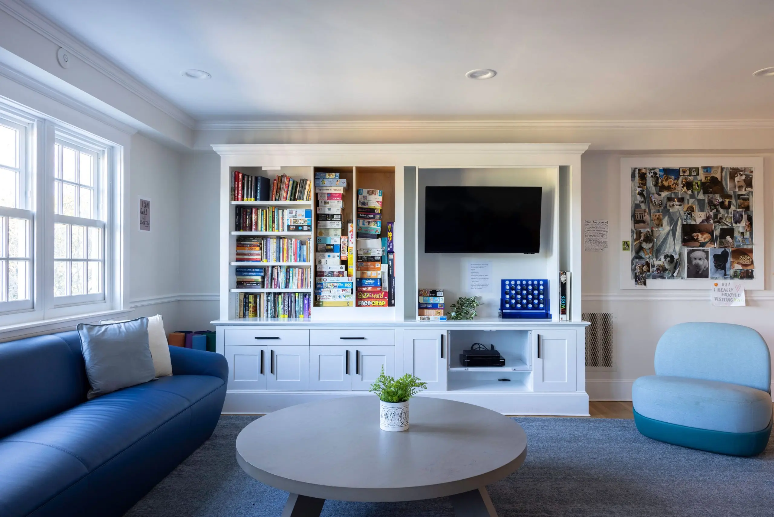 Lounge with white built-in shelving, a wall-mounted TV, a blue sofa, and a light blue chair