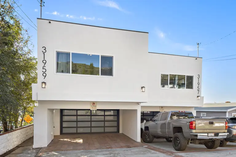 Two-story white stucco building with an attached garage and street address numbers 31959 and 31957