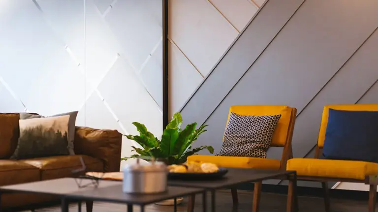Lobby with a tan leather sofa, yellow armchairs, a green plant and a coffee table