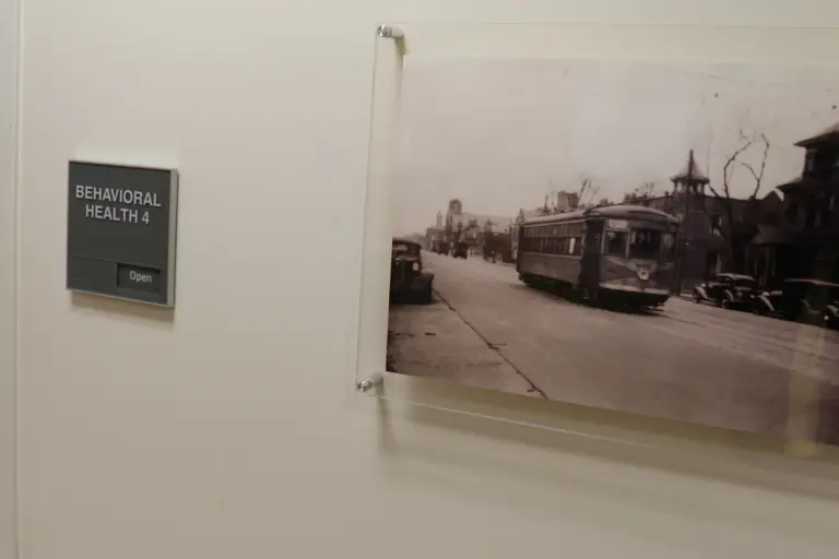 Behavioral Health 4 door sign beside a framed historic streetcar photo on a wall