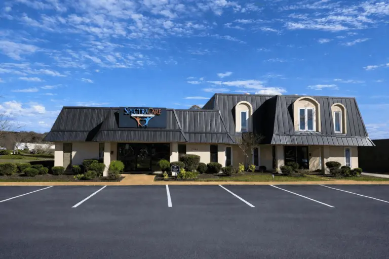 Single-story building with a SpectraCare sign above the entrance and a large parking lot in front