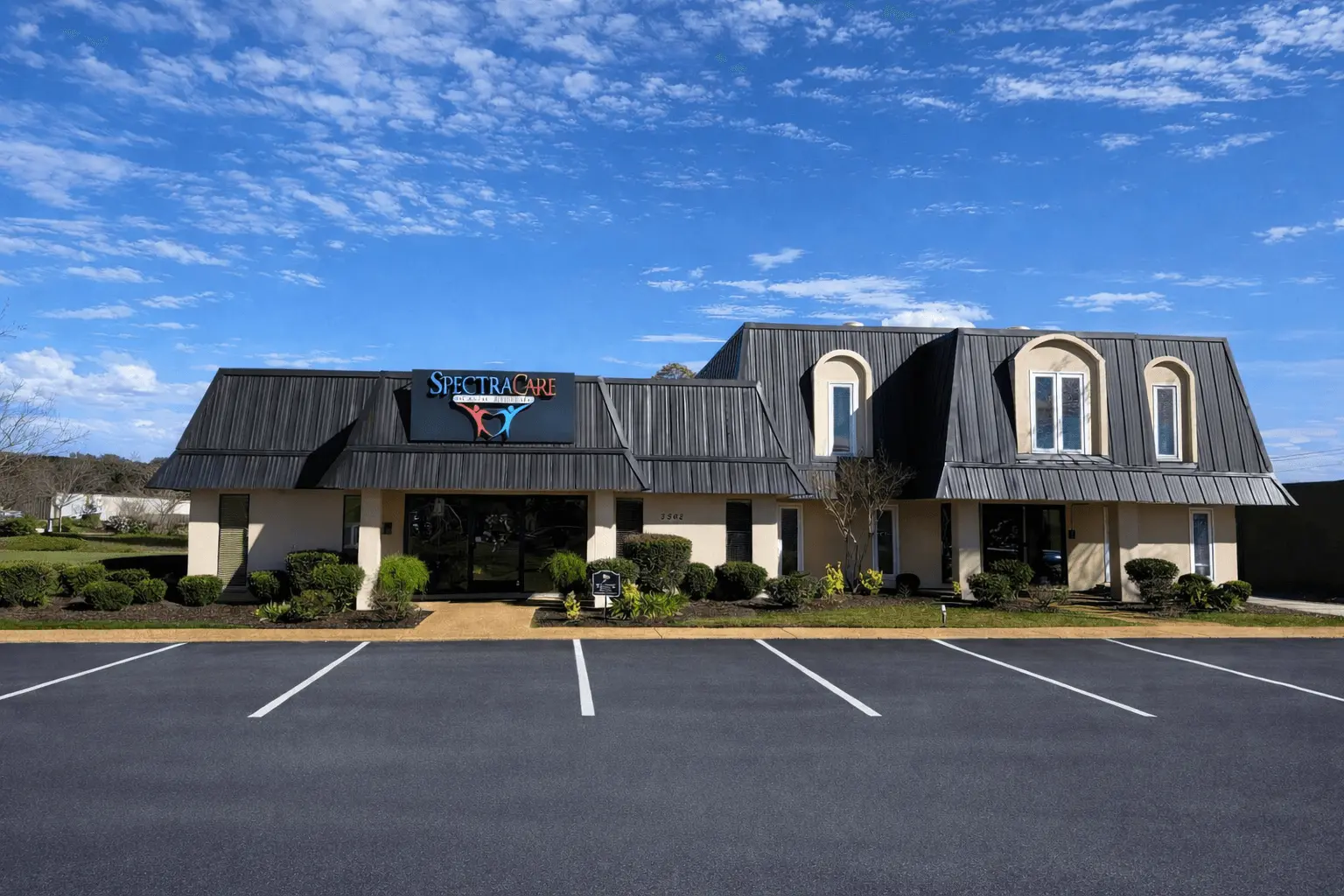 Single-story building with a SpectraCare sign above the entrance and a large parking lot in front